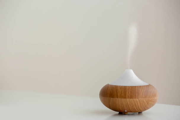 Aroma oil diffuser lamp on table against light background - Zdjęcie, obraz