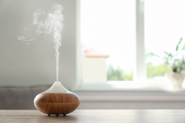 Modern aroma lamp on table against blurred background with space for text - Foto, Imagem