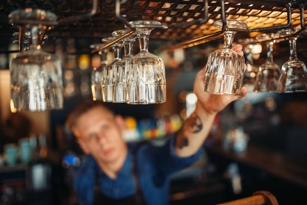 männliche Barkeeper in Schürze nimmt ein sauberes Glas von der Theke. Barkeeper Beruf, Bartending - Foto, Bild