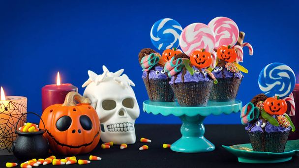 ハロウィーン キャンディランド点滴ケーキ スタイル青の背景にお菓子とカップケーキ. - 写真・画像