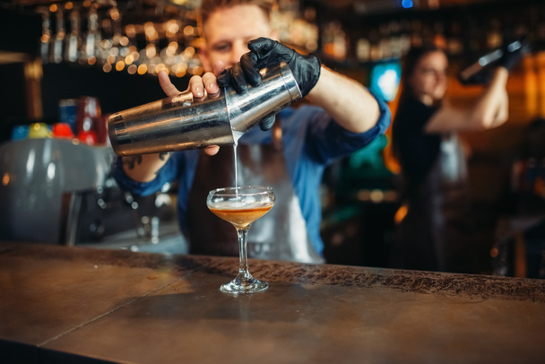 Barista maschio che versa il drink dallo shaker al bancone del bar. Preparazione di coctail alcolici. occupazione Barman, barista
 - Foto, immagini