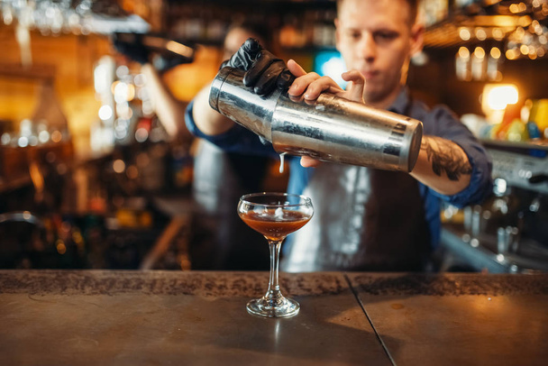Férfi csapos ömlött az italt a bárban a shaker számláló. Alkoholos koktél elkészítése. Csapos foglalkozás, bartending - Fotó, kép