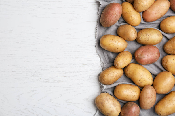 Fresh ripe organic potatoes on white wooden background, top view - Fotografie, Obrázek