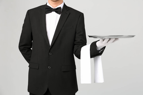 Waiter holding metal tray on light background - Foto, Imagen