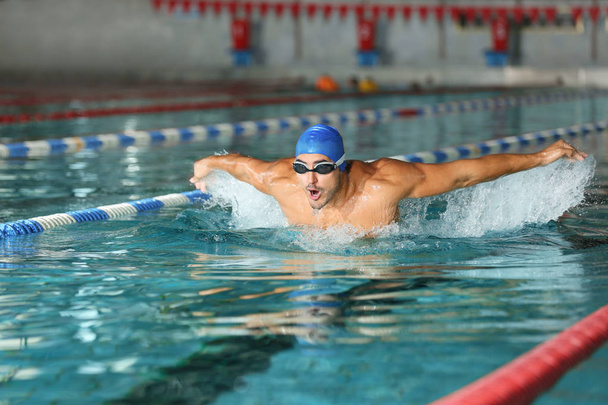 Young athletic man swimming in pool indoors - Fotó, kép