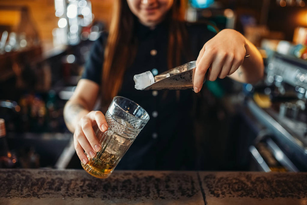 Female barman mixing at the bar counter in pub. Woman bartender prepares beverage. Barkeeper occupation - Фото, зображення