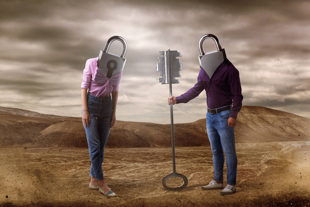 Άνδρας και γυναίκα με οπές αντί κεφάλια κατέχει μεγάλο κλειδί, έρημο σε φόντο. Ζευγάρι σχέση έννοια, μυστικό μονοπάτι στην καρδιά - Φωτογραφία, εικόνα