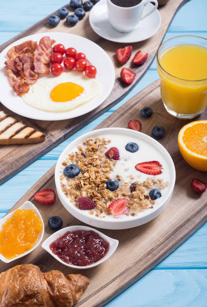 Breakfast with yogurt, eggs, berries, juice, croissant and jam - Photo, Image
