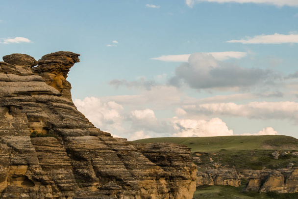 Stone cliffs overlooking rolling grass hills - Foto, imagen