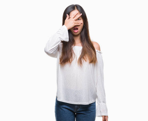 Młoda kobieta azjatyckich na białym tle wgląd w szoku pokrycie twarzy i oczy ręką, patrząc przez palce z wyrażenie zakłopotany. - Zdjęcie, obraz