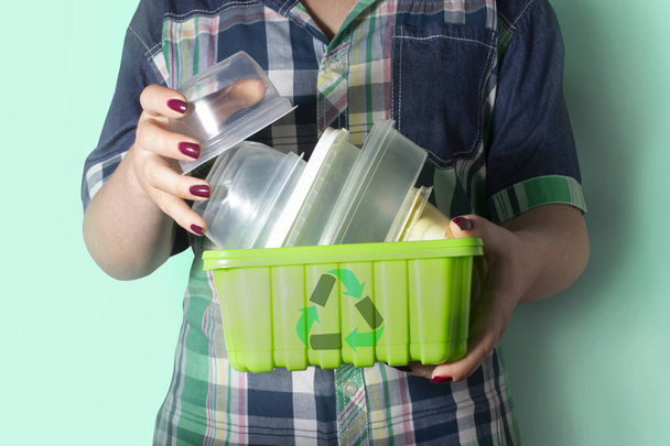 Woman's hands holding recyclable garbage - plastic containers with recycling symbol on it. Recycling, environment and ecology concept. - Photo, Image