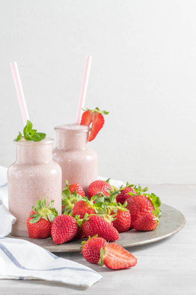 Aardbei milkshake of smoothie in glazen potten op een tafel. Biologische voeding dieet. Bovenaanzicht met kopie ruimte - Foto, afbeelding
