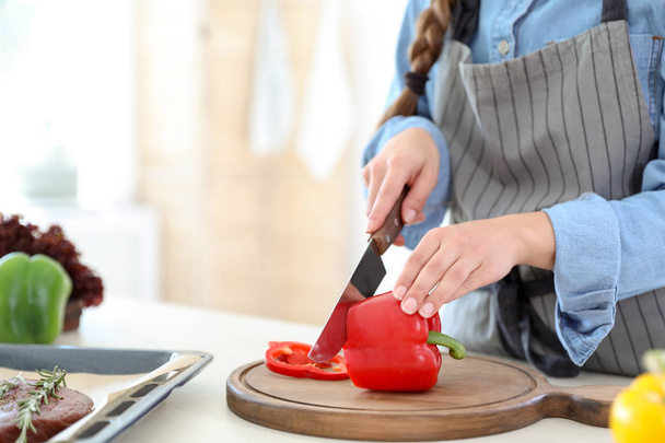 Professional female chef cutting pepper on table in kitchen, closeup - Zdjęcie, obraz
