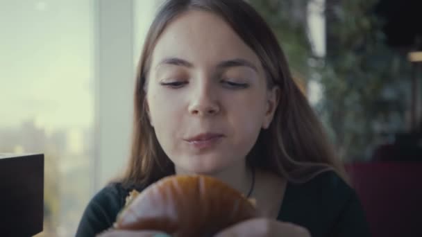 Görüntüleri genç kadın fast food restoranında lezzetli hamburger yemek. - Video, Çekim
