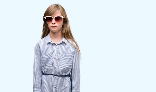 Jeune bambin blonde portant une chemise bleue avec une expression confiante sur la pensée intelligente du visage sérieux
 - Photo, image