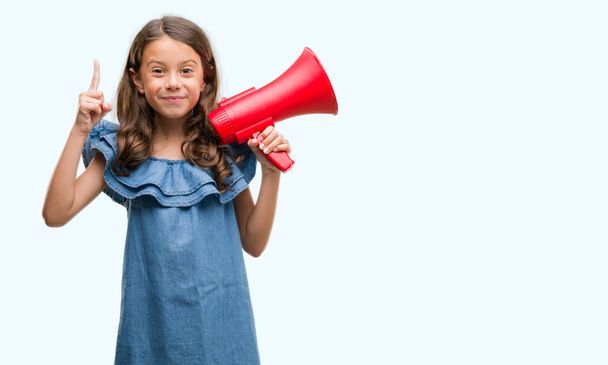 Брюнетка латиноамериканського дівчина Холдинг червоний Мегафон здивований ідеї або питання вказівним пальцем з щасливим обличчям, номер один - Фото, зображення