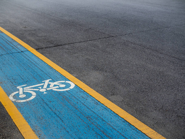 Pista ciclabile. Icona bianca per bicicletta su sfondo blu e giallo sulla vecchia strada con spazio per copiare
. - Foto, immagini