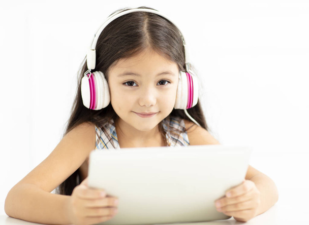smiling girl in headphone and using  tablet  - Фото, изображение