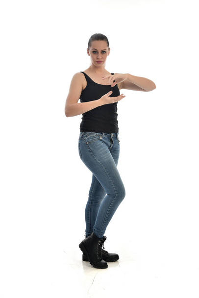 ritratto a figura intera di ragazza bruna che indossa singolo nero e jeans. in piedi posa. isolato su sfondo bianco dello studio
. - Foto, immagini