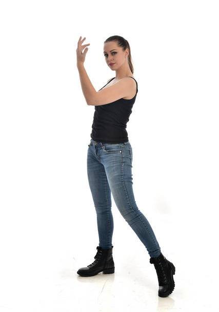 portrait complet de fille brune portant unique noir et jeans. pose debout. isolé sur fond de studio blanc
. - Photo, image