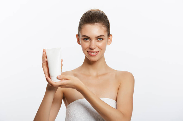 Beauty Youth Skin Care Concept: hermoso retrato facial de mujer caucásica que sostiene y presenta el producto de tubo de crema. Hermosa modelo de spa Chica
. - Foto, Imagen