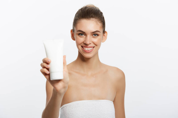 Beauty Youth Skin Care Concept - Beautiful Caucasian Woman Face Portrait holding and presenting cream tube product. Beautiful Spa model Girl. - Fotó, kép