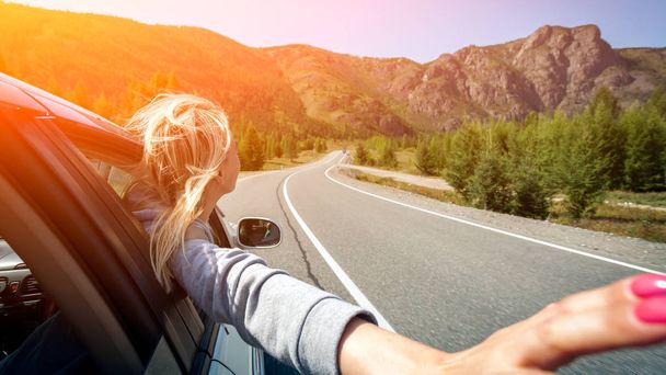 Sarışın bir kadın kafasını testere dişi dağ manzaralı bir sürücü zevk pencereden dışarı ile. Güneş parlıyor. Arkadan ateş - Fotoğraf, Görsel