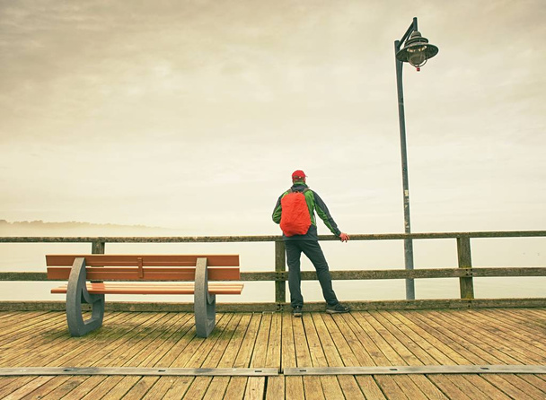 Man reiziger op het einde van de pier Bekijk de verre horizon. Moody's morgens op de brug van de zee - Foto, afbeelding
