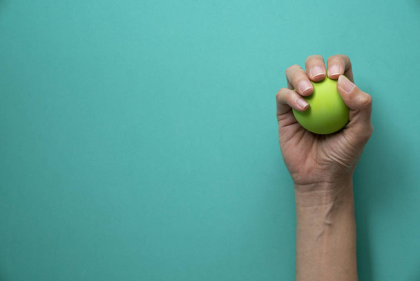 woman holding stress ball on green background - Foto, afbeelding
