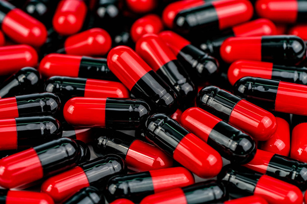 Pile of red-black capsule pills. Antibiotics resistance. Drug use with reasonable. Global healthcare concept. Antibiotics drug resistance. Antimicrobial capsule pills. Pharmaceutical industry. - Photo, Image