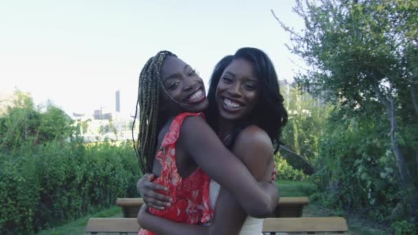 Shot piękny zwolnionym tempie dwóch African American kobiet, przytulanie i uśmiechając się do kamery z centrum Los Angeles w tle - Materiał filmowy, wideo
