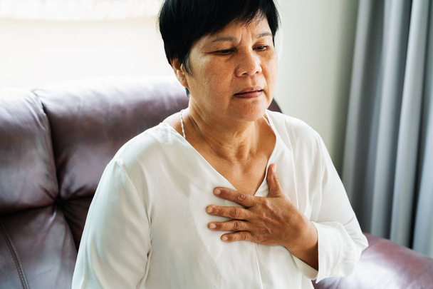ηλικιωμένη γυναίκα παθαίνει καρδιακή προσβολή και αρπάζει το στήθος της - Φωτογραφία, εικόνα