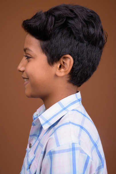 Young Indian boy wearing checkered shirt against brown backgroun - Photo, Image