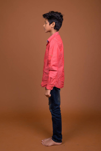 Young Indian boy wearing smart casual clothing against brown bac - Fotoğraf, Görsel