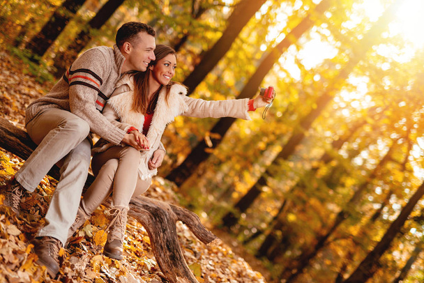 couple souriant profiter et prendre selfie sur appareil photo numérique dans la forêt d'automne
 - Photo, image