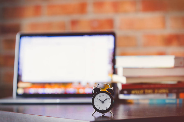 alarm clock on a table with laptop computer and books - 写真・画像