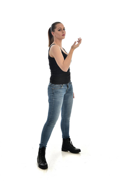 portrait complet de fille brune portant unique noir et jeans. pose debout. isolé sur fond de studio blanc
. - Photo, image