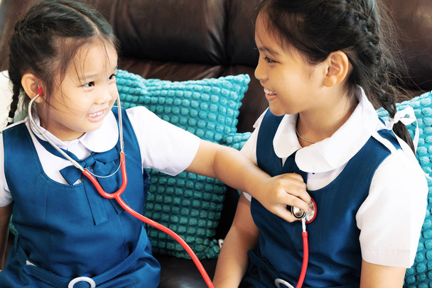 két kislány mosolyog és játszik orvos sztetoszkóp. Gyerek és egészségügyi koncepció. - Fotó, kép