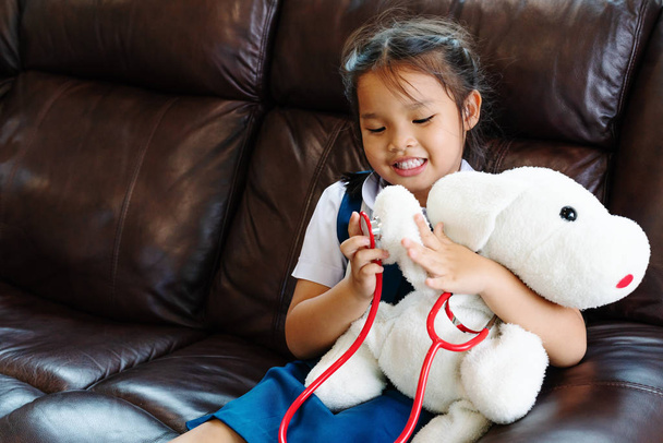 少女は笑みを浮かべて、聴診器で医者を再生します。子供と医療の概念. - 写真・画像