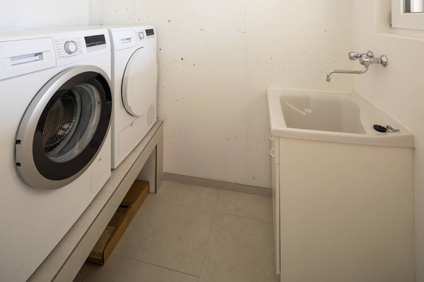 Laundry with washing machine, dryer and sink. Nobody inside - Фото, изображение