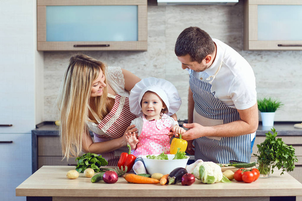 Een gelukkige familie bereidt gerechten uit groenten in de keuken - Foto, afbeelding