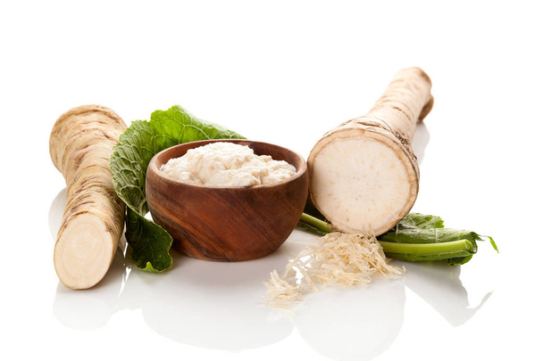 Fresh and grated horseradish in wooden bowl isolated on white background. - Photo, Image