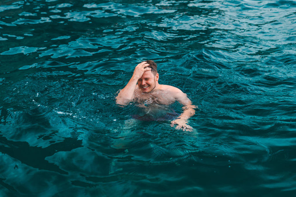 mies ui sinisessä läpinäkyvässä merivedessä. kesäloma
 - Valokuva, kuva