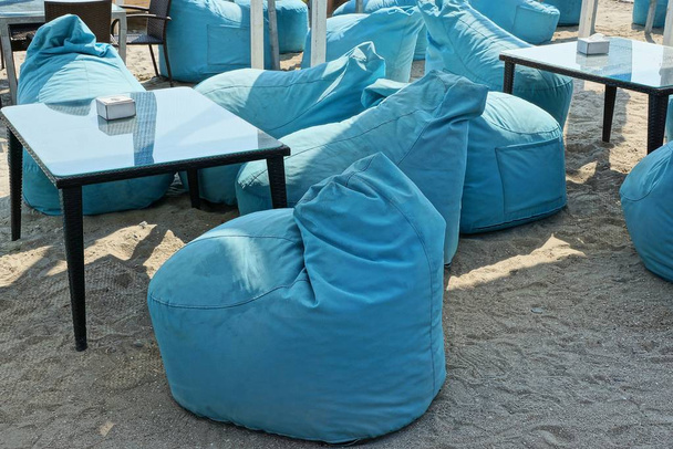 μαύρα τραπέζια και μπλε εισπνοές για να κάθεται στην άμμο στην παραλία σε ένα εστιατόριο το καλοκαίρι - Φωτογραφία, εικόνα