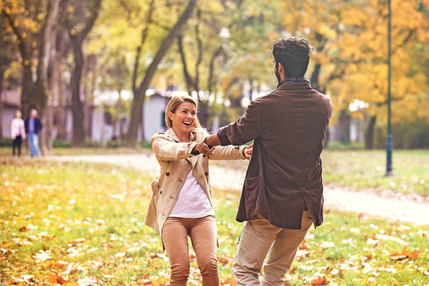 公園の若いカップルを楽しんで笑顔秋します。. - 写真・画像