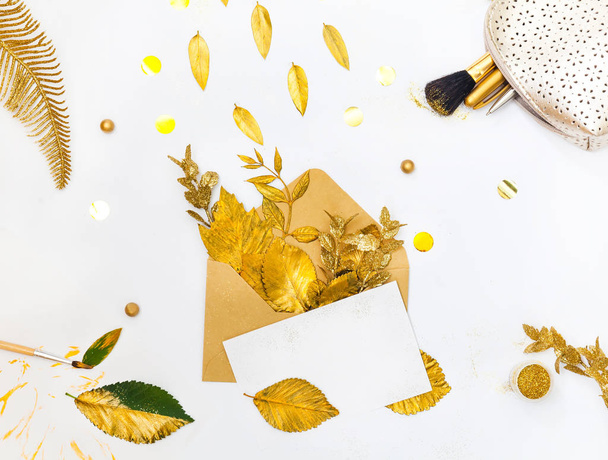 Golden Styled desk with envelope, blank card, composition of golden leaves and gold creative stuff. Flat lay. - Fotografie, Obrázek