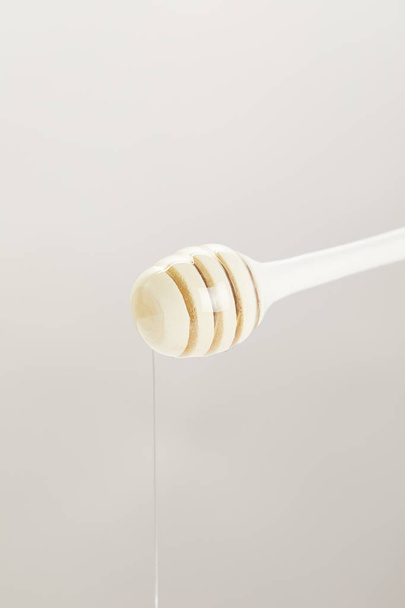 close up view of wooden honey deeper with organic honey on grey background - Foto, immagini