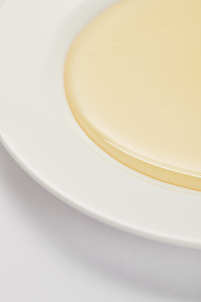 vista ravvicinata di miele naturale su piatto su superficie bianca
 - Foto, immagini