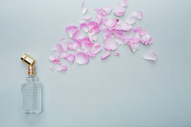 garrafa de perfume com cheiro de flores no fundo azul. perfume com spray de pétalas de flores vista superior
 - Foto, Imagem