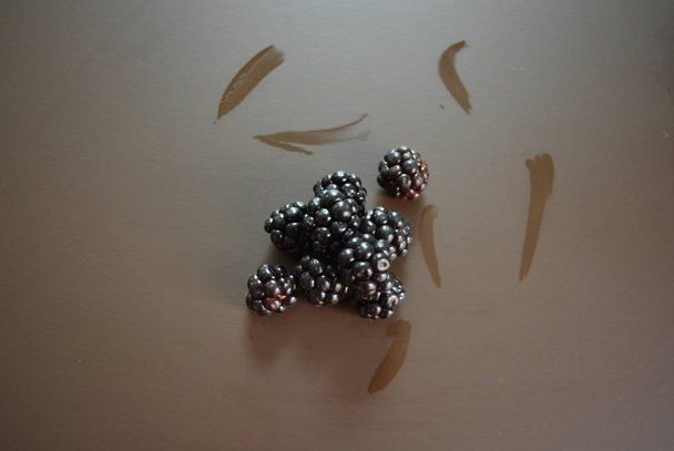 Vastapoimittuja karhunvatukoita vedellä ruskealla matta taustalla
 - Valokuva, kuva